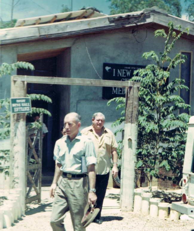 Colour photograph of two men leaving a building