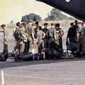 Military plane on runway with men in green uniforms standing next to it