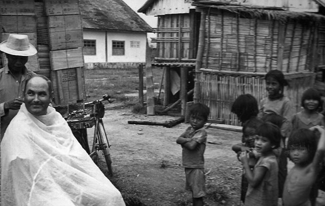 Ken Treanor receives haircut in Montagnard village, circa 1968