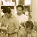 Three men reading books in a room filled with medical supplies.
