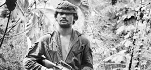 Soldier wearing uniform in jungle holding gun.